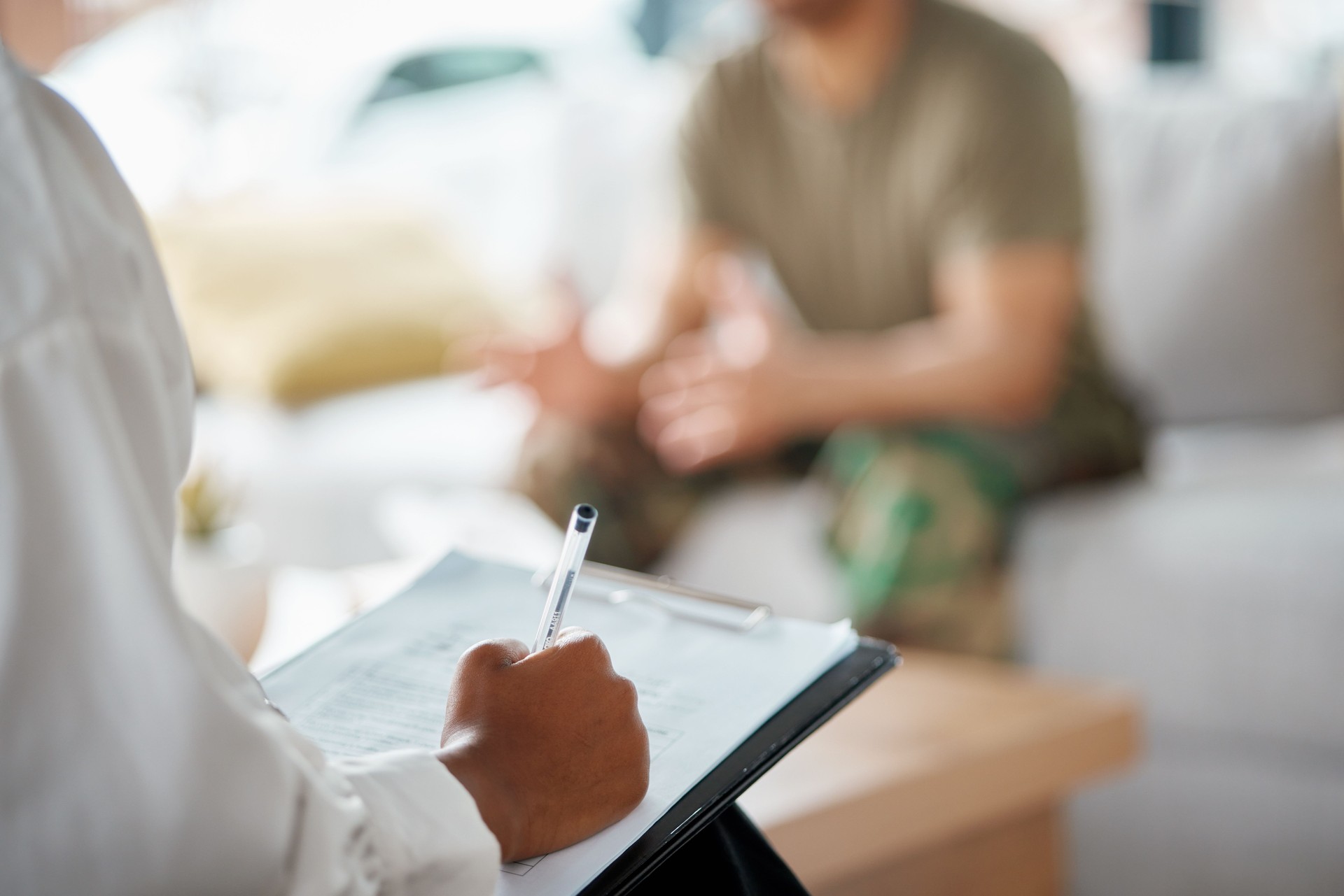 Closeup, psychologist and counselling with therapy, writing or conversation with health, military or diagnosis. Psychology, patient or review with analysis, consulting person or advice with documents